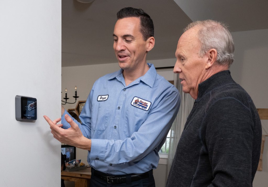 HVAC technician showing homeowner how to operate a smart thermostat