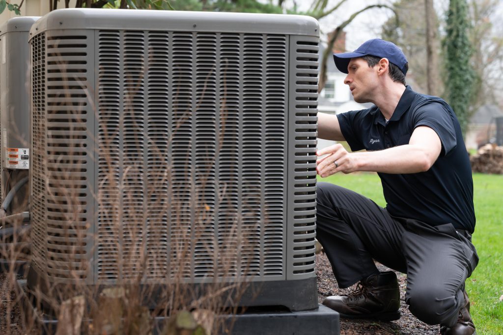 A cooling technician repairing an AC unit outside.